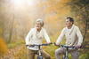 a woman and man each on a bicycle outdoors surrounded by trees